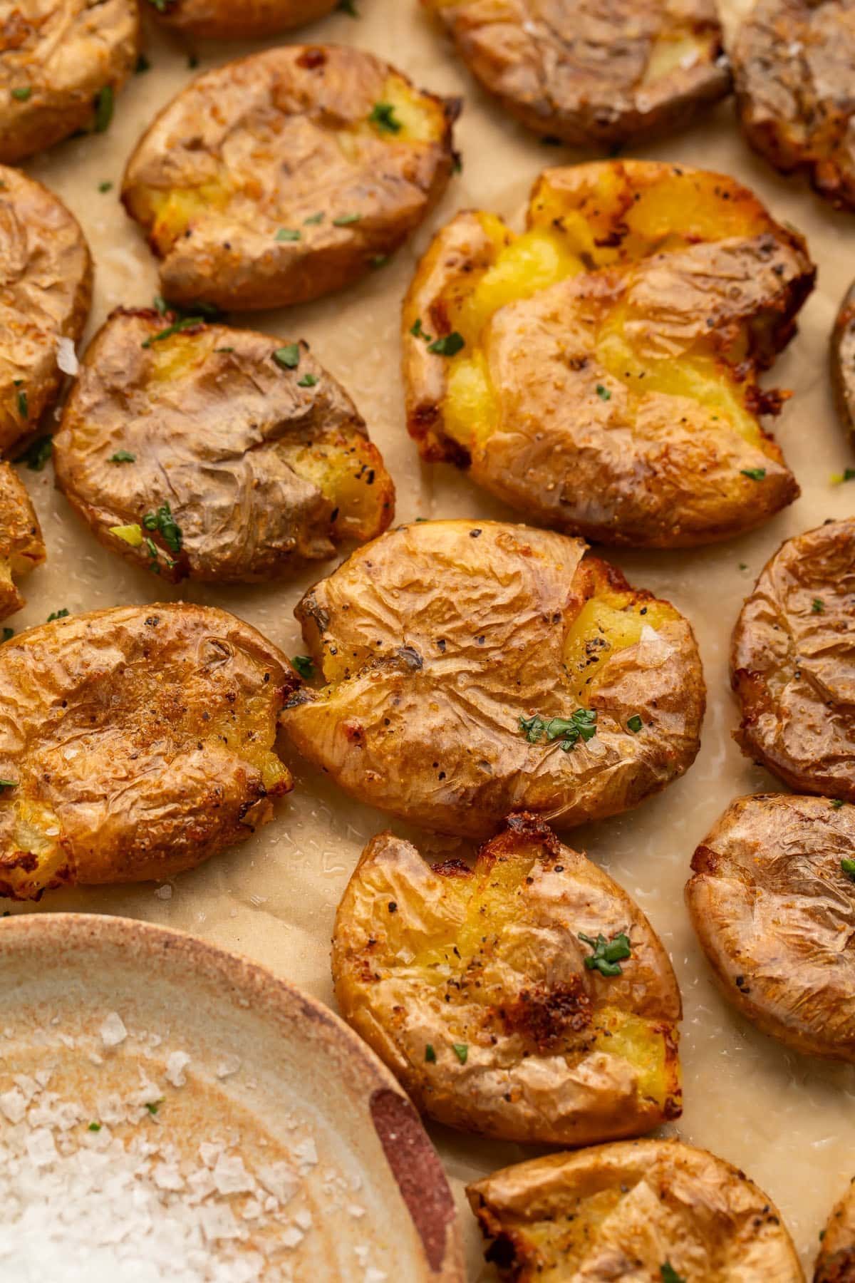 Smashed, air fried baby gold potatoes on parchment paper.