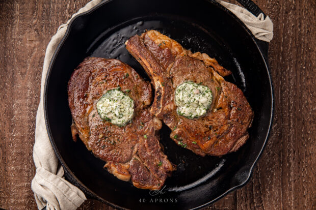 Two seared ribeyes in a cast-iron skillet