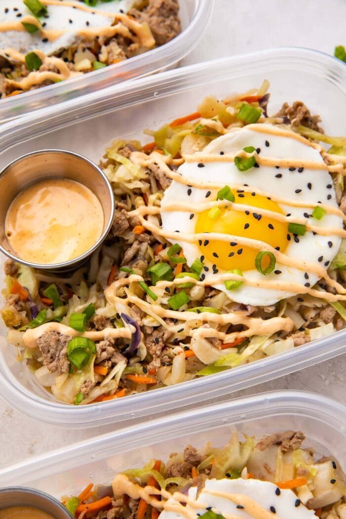 Close up of Egg roll in a bowl with a fried egg in meal prep containers