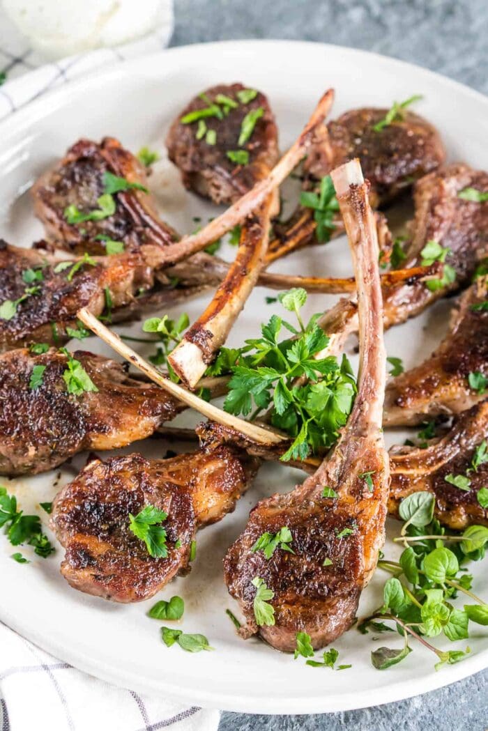 8 lamb chops with garnish on a white plate