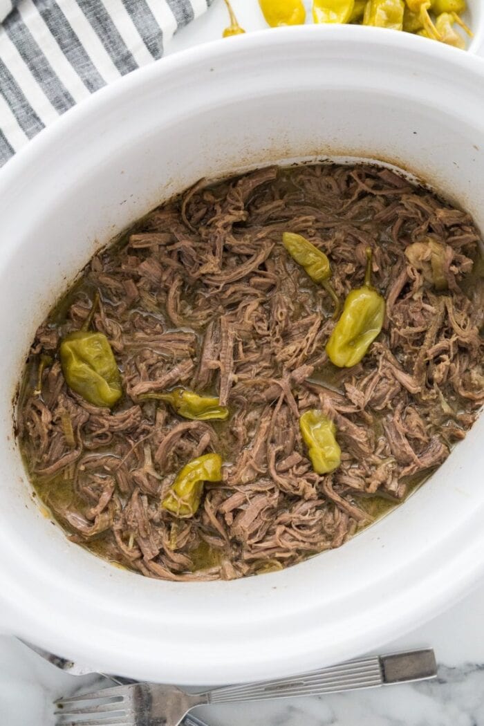 Slow cooker pot roast in a white slow cooker dish