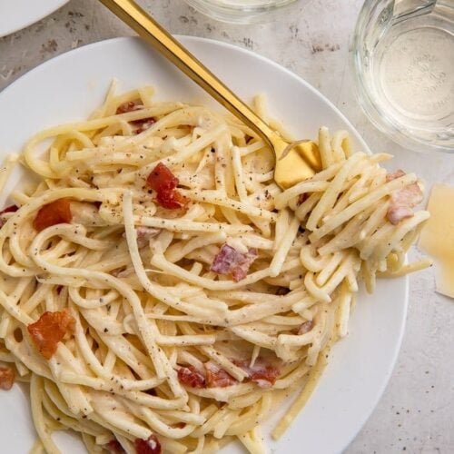 A white plate of keto carbonara with a golden fork