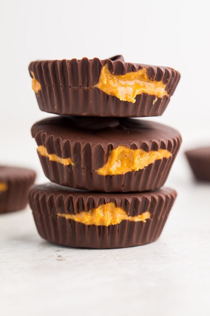 Zoomed out image of 3 keto peanut butter cups stacked on a white background