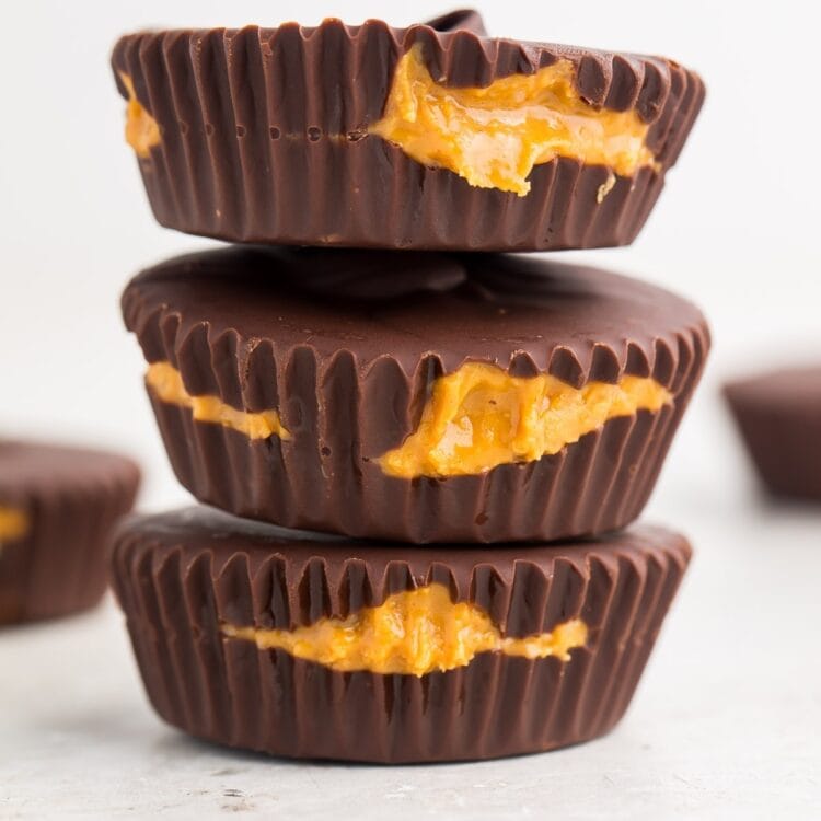 Zoomed out image of 3 keto peanut butter cups stacked on a white background