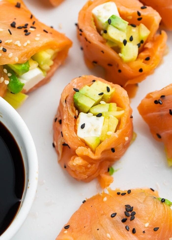 Several pieces of keto smoked salmon sushi next to a bowl of soy sauce