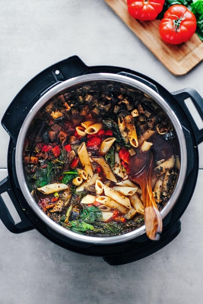 Marinara pasta and veggies in an Instant Pot with a wooden spoon