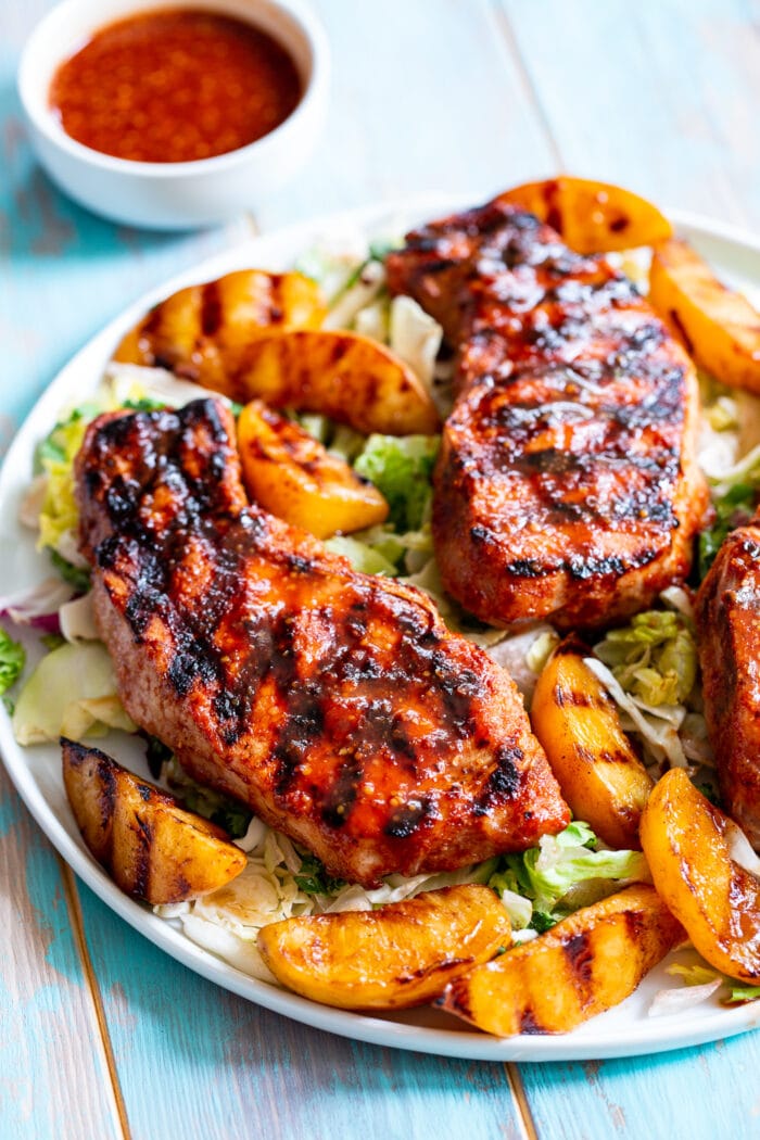 Paleo grilled pork chops with grilled peaches on a white plate