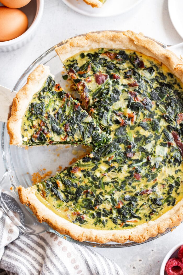Spinach quiche with one wedge shaped slice missing