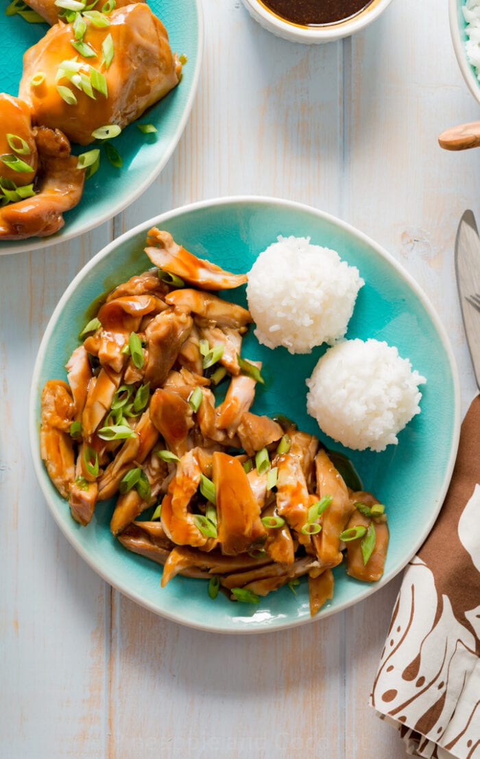 On a teal plate sits Hawaiian chicken and balls of rice