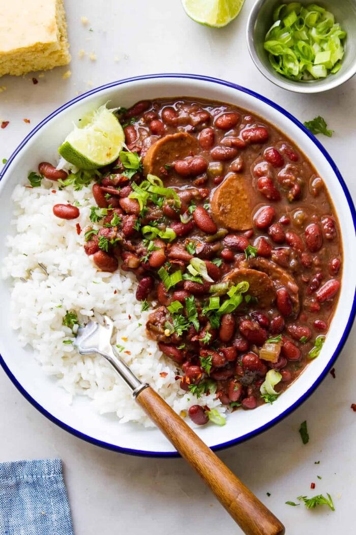 Close up photo of a bowl of red beans and vegan sausage with white rice and garnish