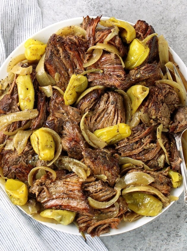 A white plate full of italian beef and veggies