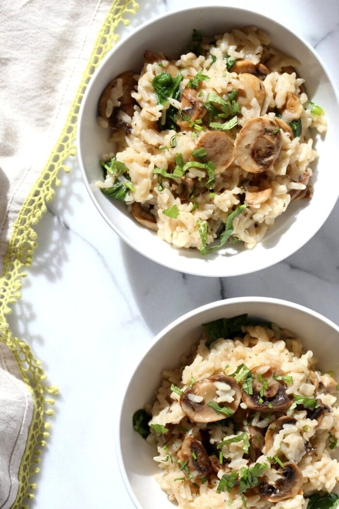 One and a half bowls of mushroom risotto on a white table