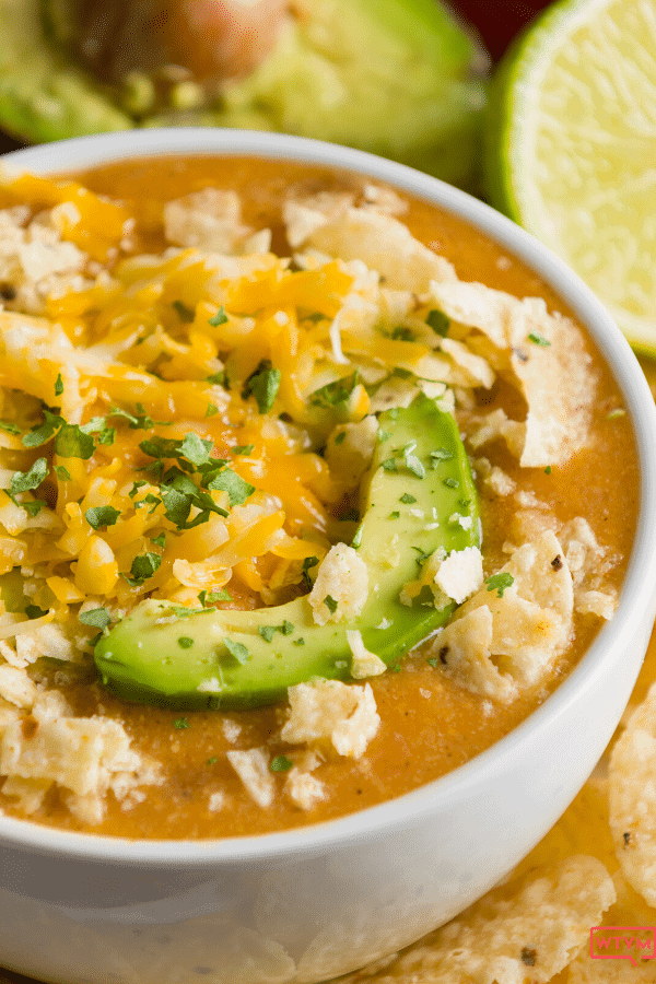 A half view of a bowl of keto chicken white chili with an avocado slice
