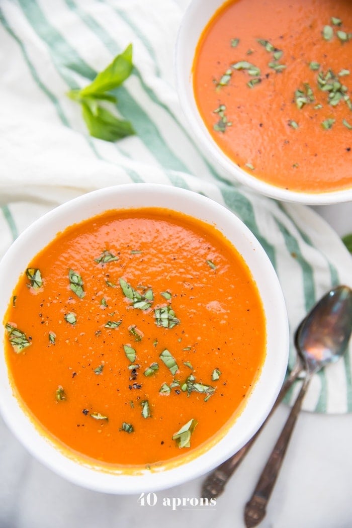 Overhead angle of two white bowls holding bright red tomato soup
