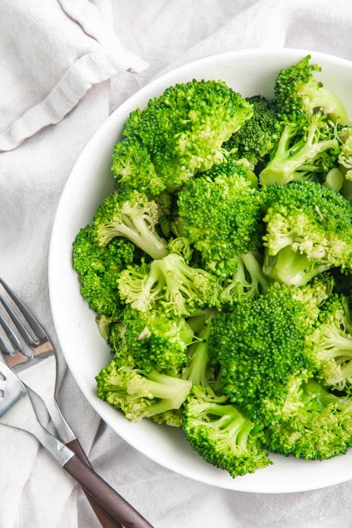 Overhead partial view of broccoli in a white bowl