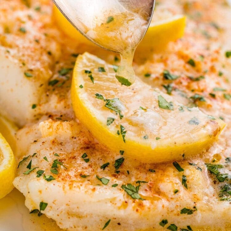 A close up of lemon garlic butter spooned over baked fish