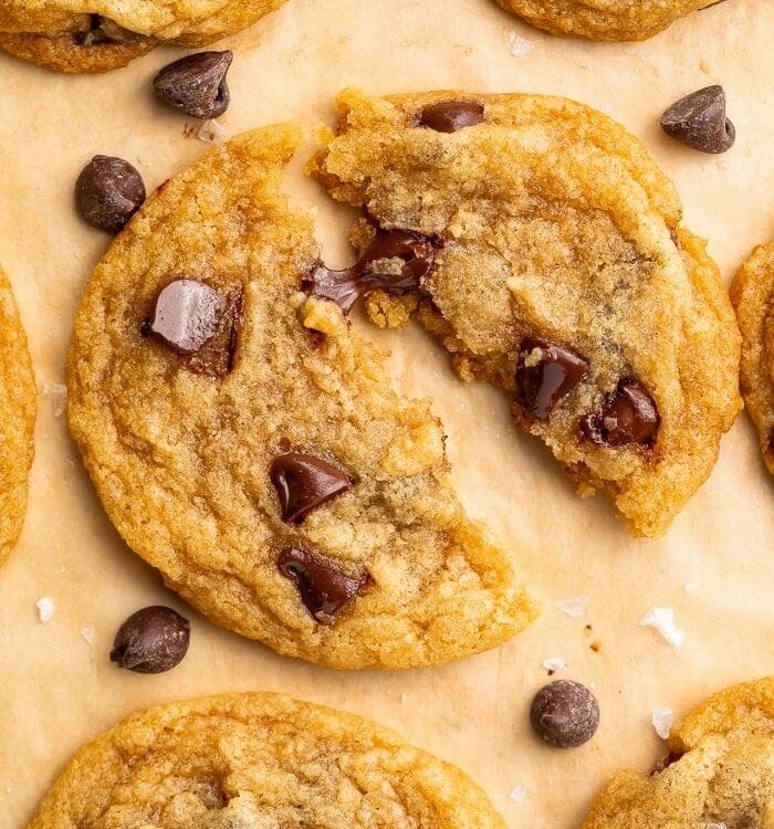 Close up of a vegan chocolate chip cookie broken in half and placed on parchment paper