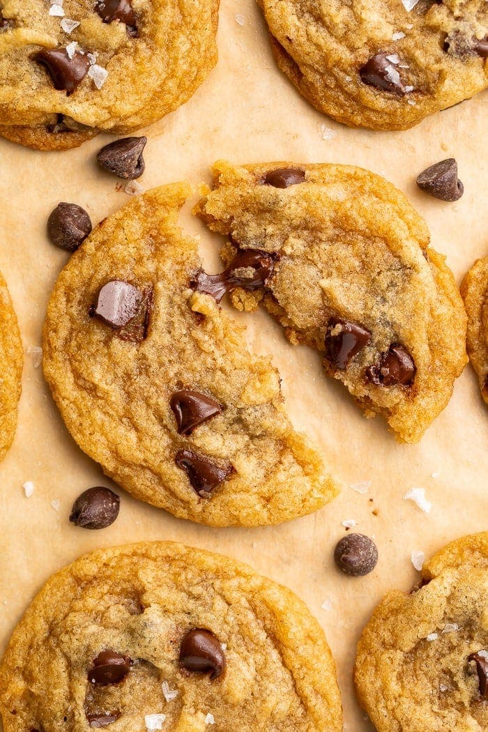 Close up of a vegan chocolate chip cookie broken in half and placed on parchment paper