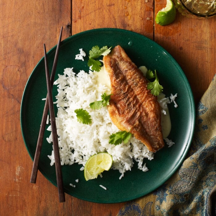 Orange roughy and white rice on a green plate with chopsticks