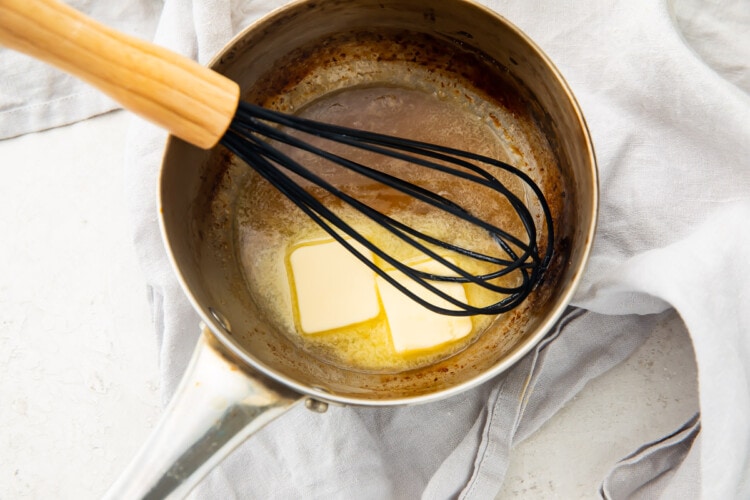 Lemon juice and chilled butter in a silver saucepan with a whisk