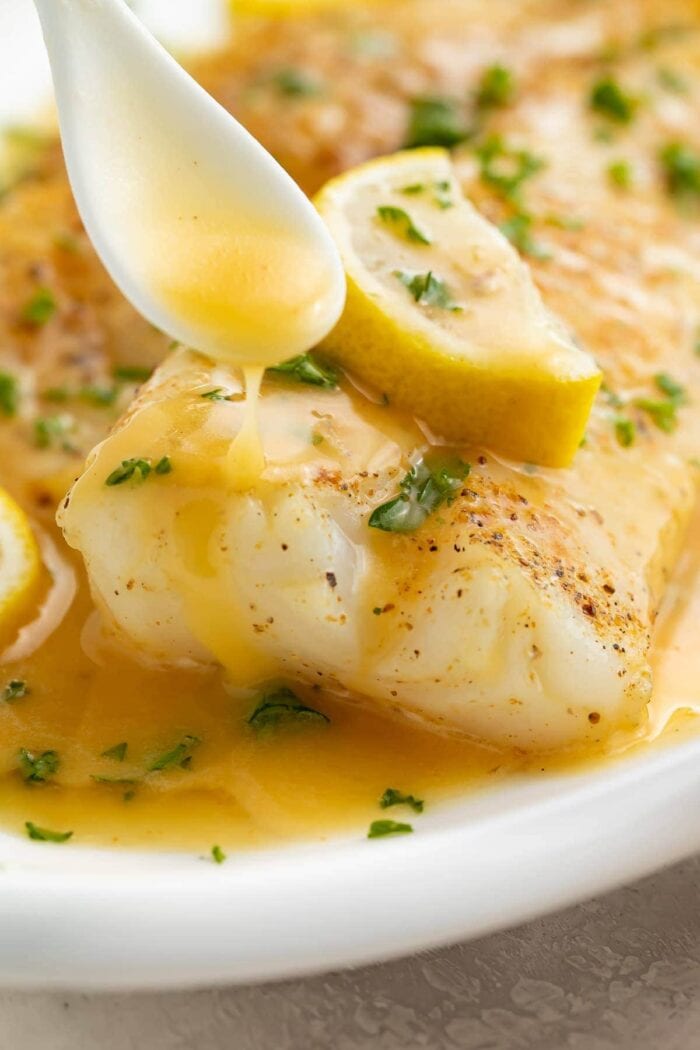 Lemon butter sauce drizzled over fish on a white platter