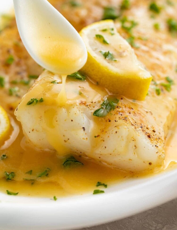 Lemon butter sauce drizzled over fish on a white platter