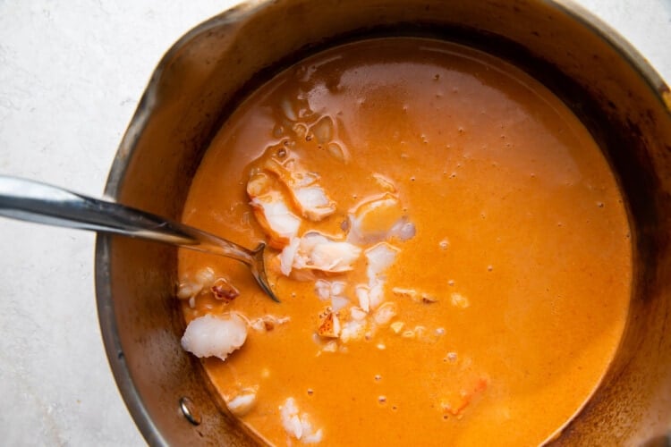 Lobster bisque in a large saucepan with a large silver ladle