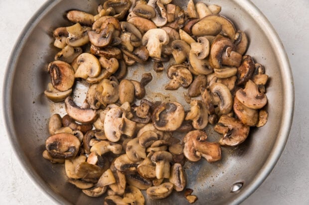 Mushrooms sautéed in butter in a silver saucepan