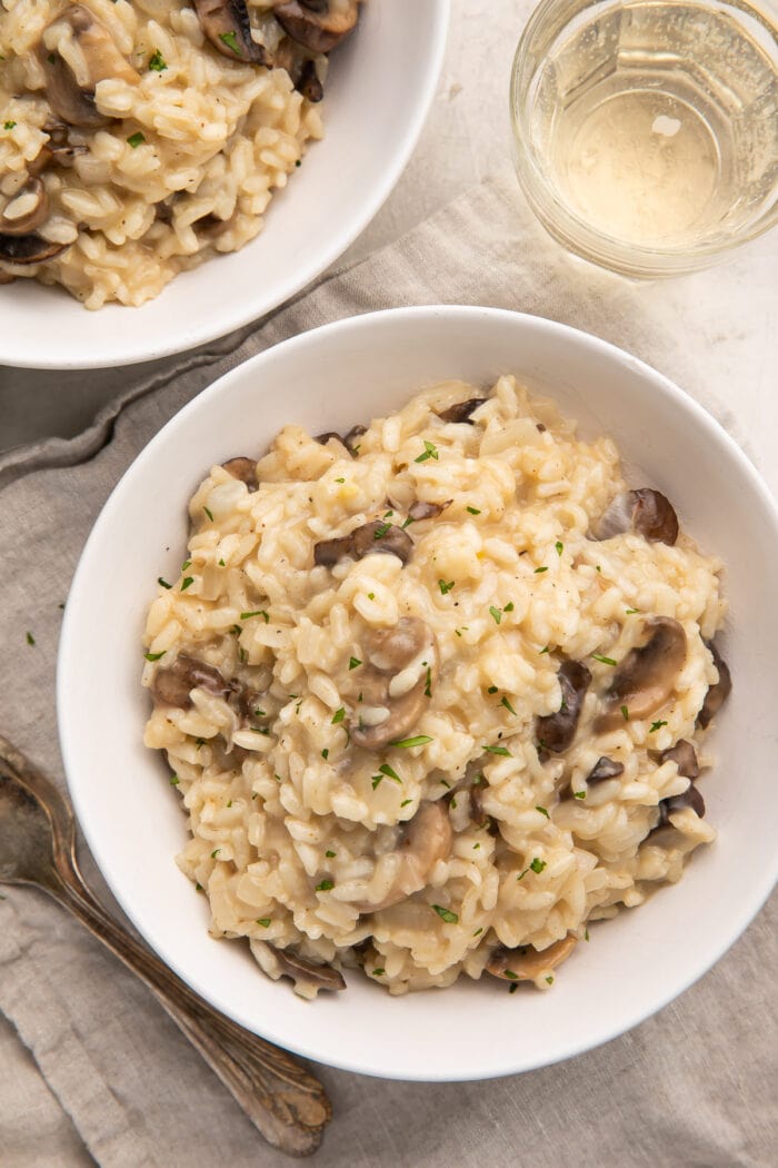 Zoomed out photo of two white shallow bowls holding mushroom risotto
