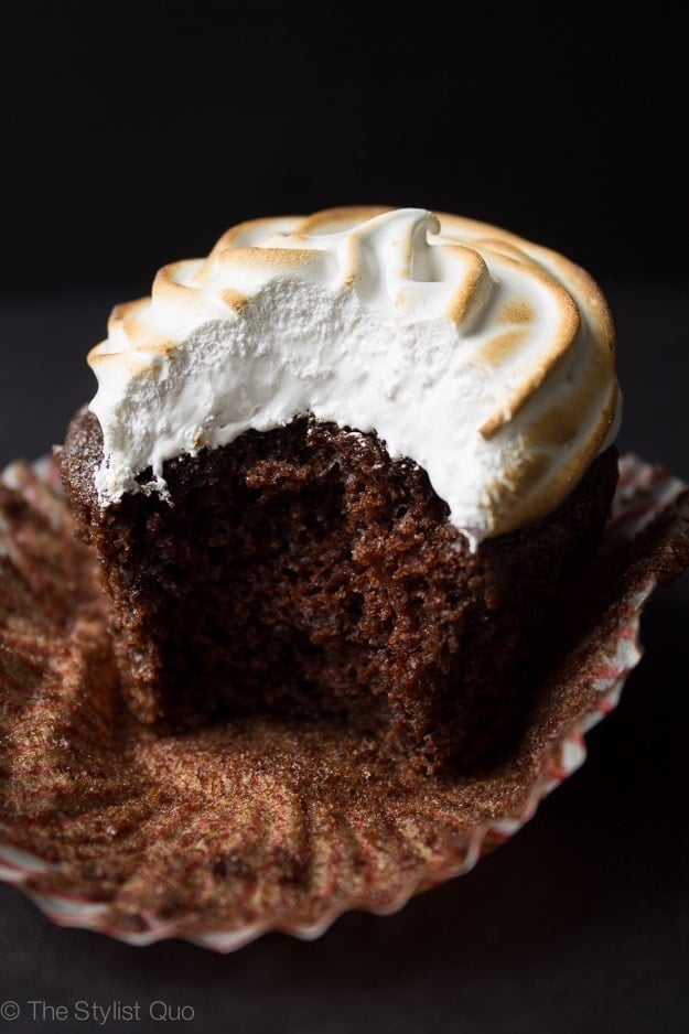 Hot chocolate cupcake topped with egg white toasted marshmallow frosting with one bite taken 
