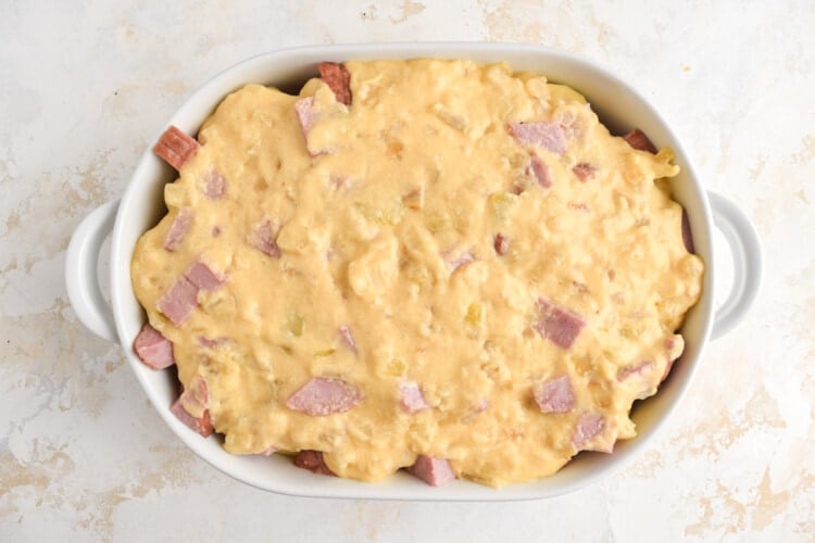 Cheesy potato and ham casserole, uncooked, in a white casserole dish