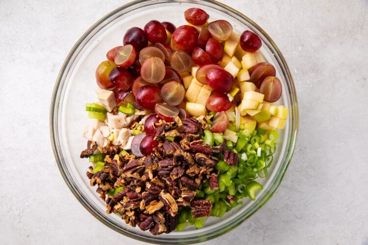 Ingredients for chicken salad with grapes and pecans in a glass mixing bowl