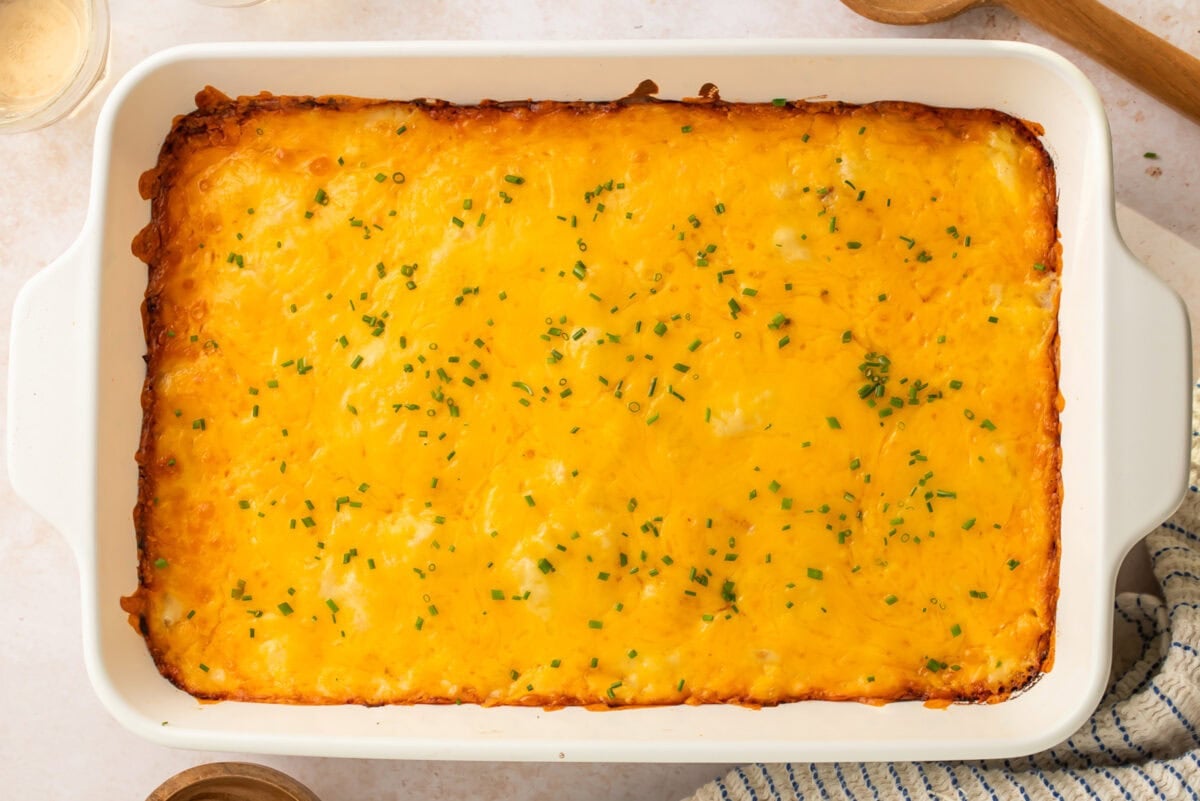 Cheesy ham and potato casserole in a rectangular white casserole dish.