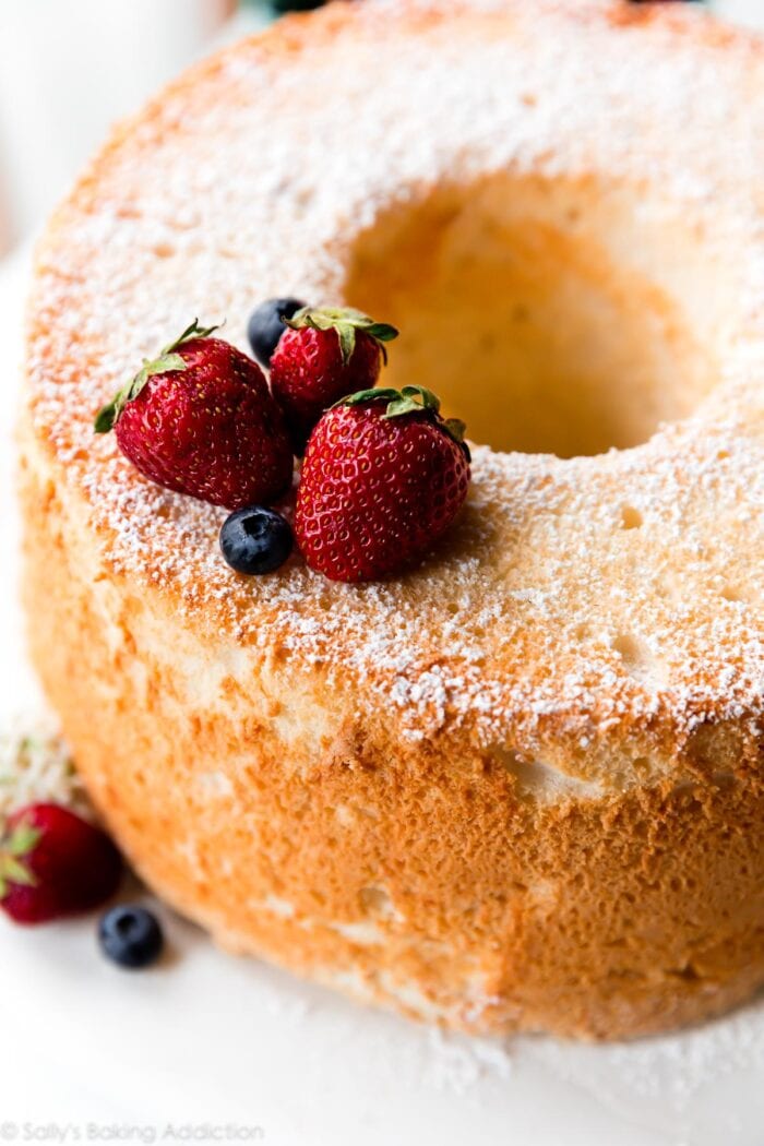 Angel food cake lightly dusted with powdered sugar and topped with blueberries and strawberries
