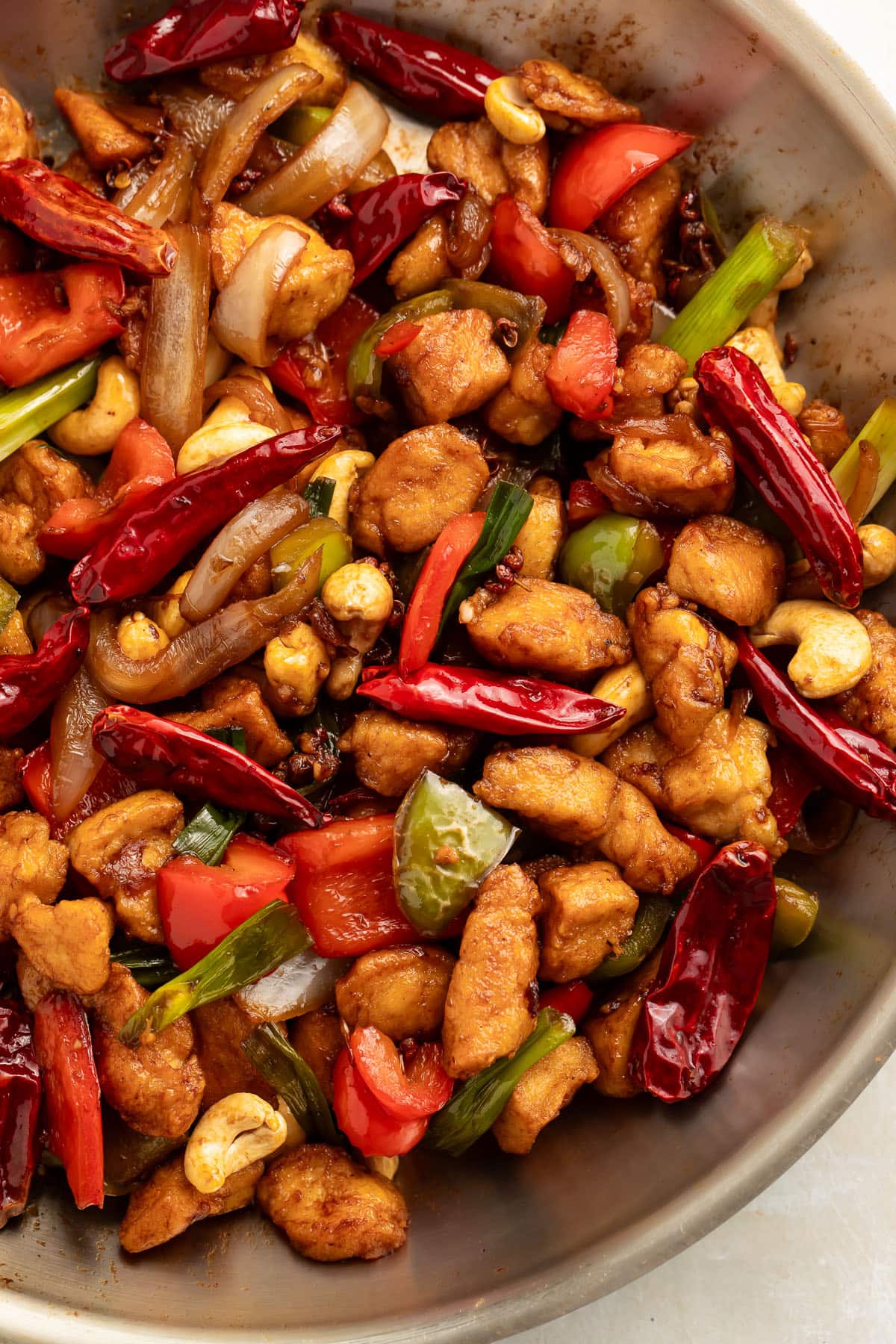 Top-down view of a large wok holding prepared Szechuan chicken with cashews, chilies, peppercorns, and chicken.