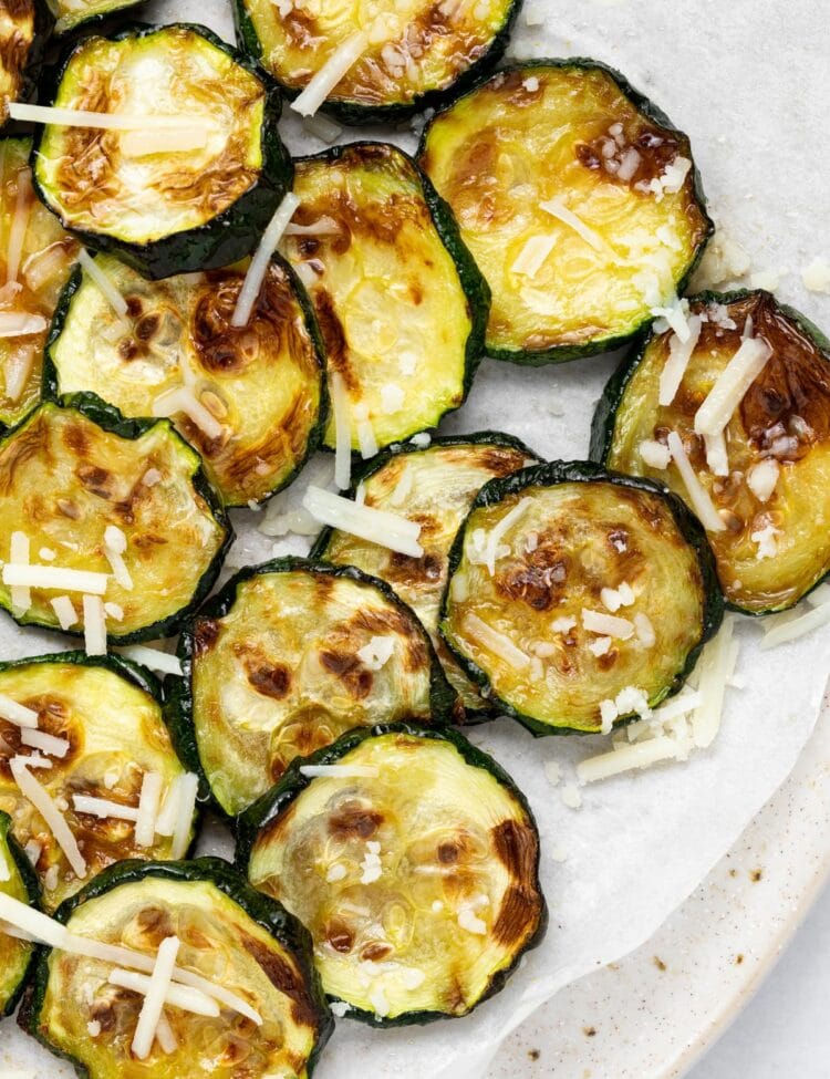 Overhead image of air fried zucchini slices with parmesan cheese on top.