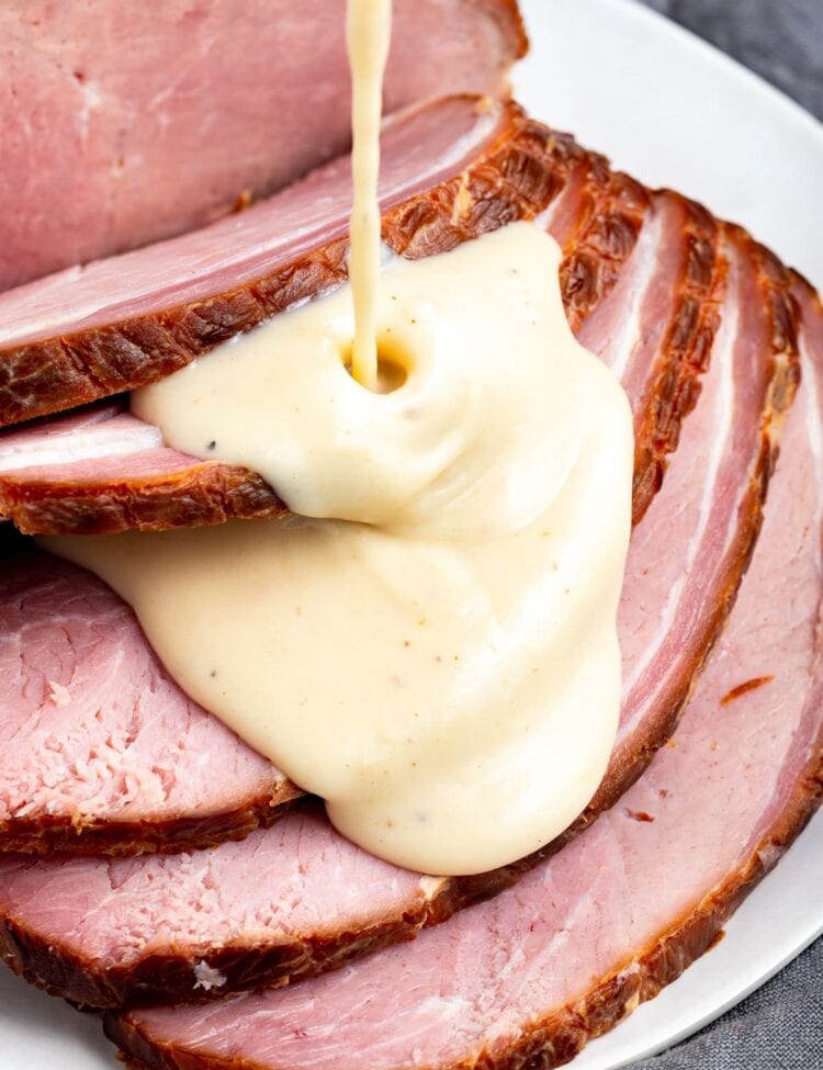Sliced ham with ham gravy being poured over the top.