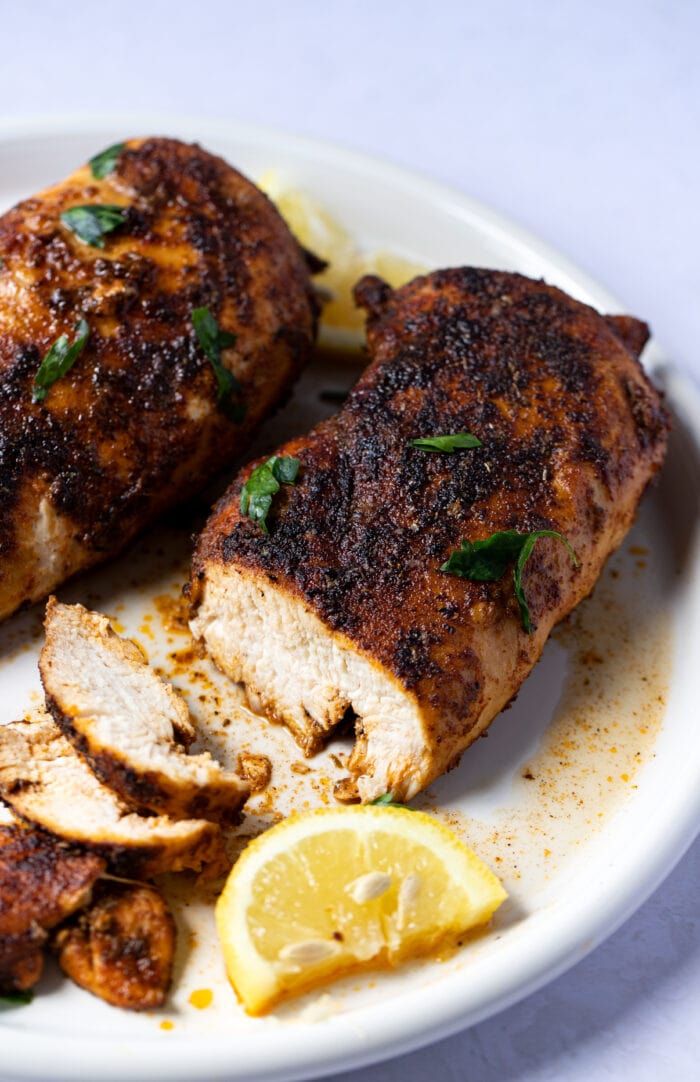 Blackened chicken on a white plate, sliced to show meat inside