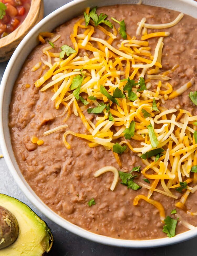 Instant Pot refried beans in a bowl topped with shredded cheese