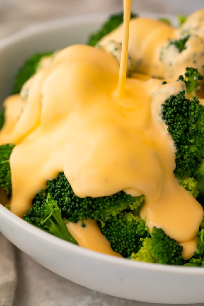 Keto cheese sauce smothering a bowl of broccoli florets