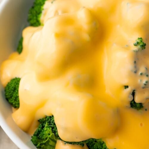 Keto cheese sauce smothering a bowl of broccoli florets