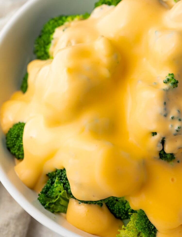 Keto cheese sauce smothering a bowl of broccoli florets