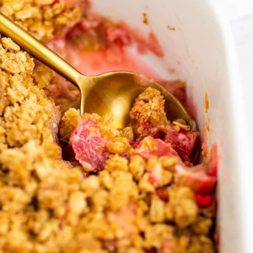 Rhubarb crumble close-up picture, being scooped with a gold spoon.