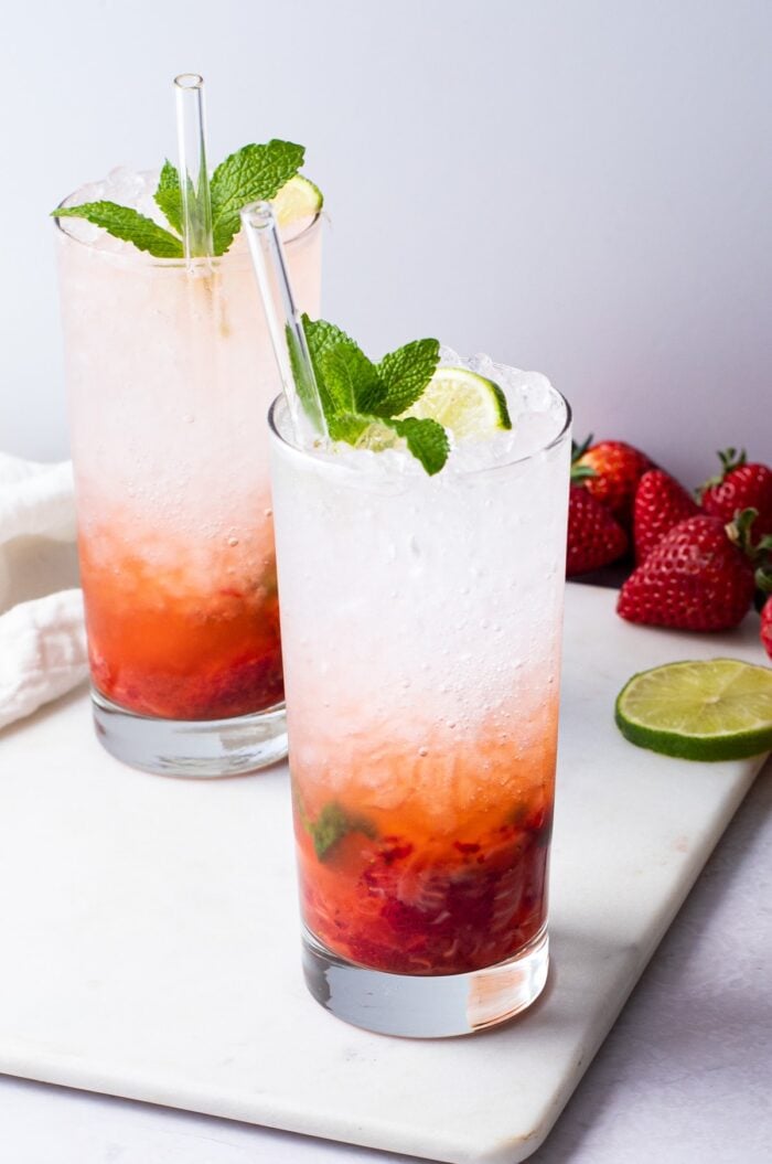 2 strawberry mojitos in tall glasses with ice and mint leaves