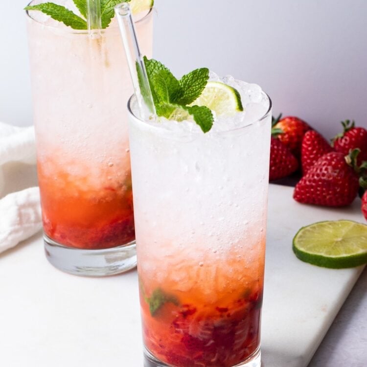 2 strawberry mojitos in tall glasses with ice and mint leaves