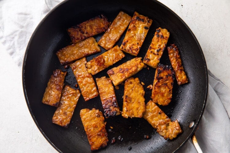 Marinated tempeh bacon in large skillet