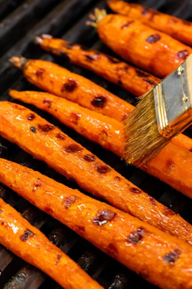 maple syrup being brushed on maple glazed grilled carrots