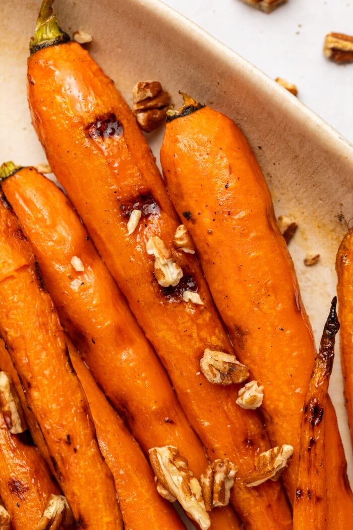 maple glazed grilled carrots in a serving dish with chopped pecans on top