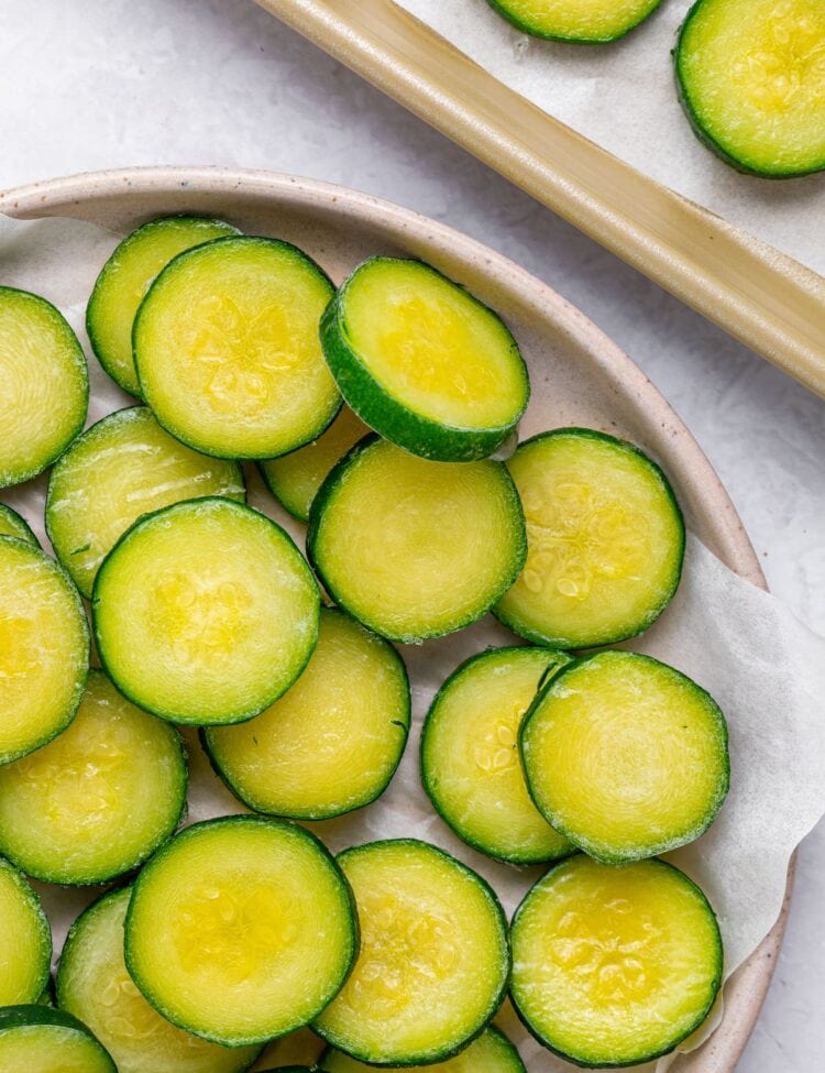 frozen sliced zucchini on a plate and on a baking tray