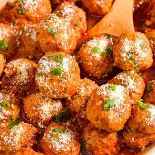 Close up image of instant pot meatballs in a serving dish with a wooden spoon.